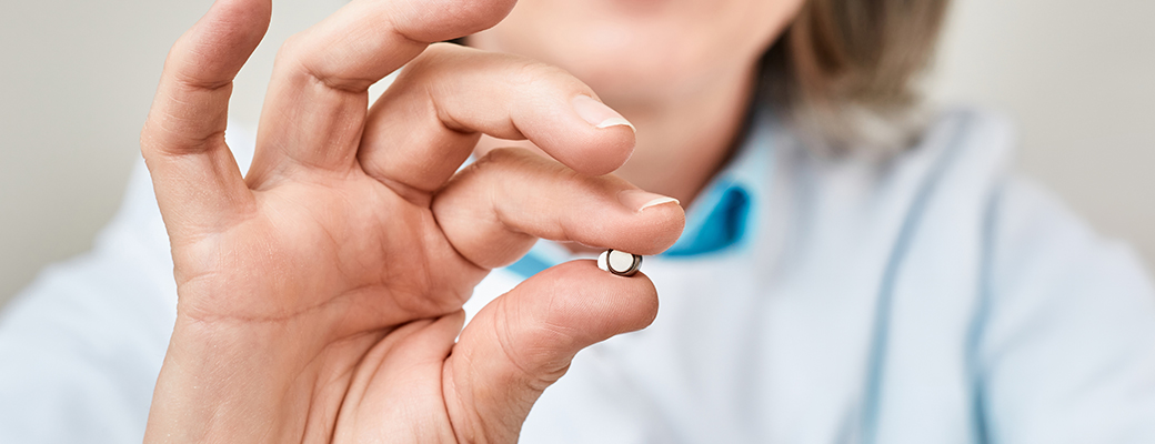 Image of hand holding a hearing aid battery